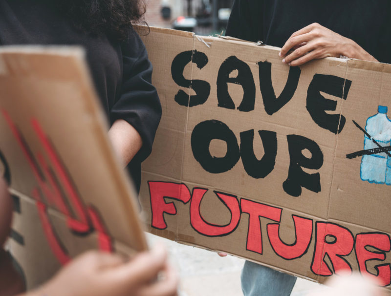 Människor håller handmålade skyltar, på en skylt texten "Save our future".